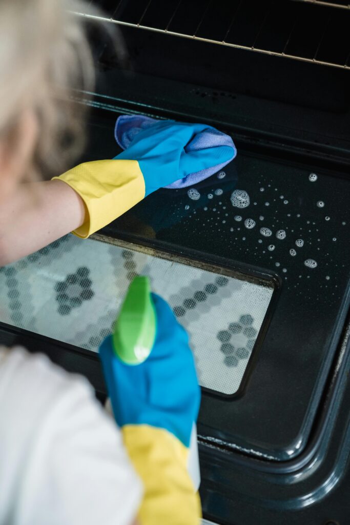 Close-up of a woman cleaning the interior oven mirror.