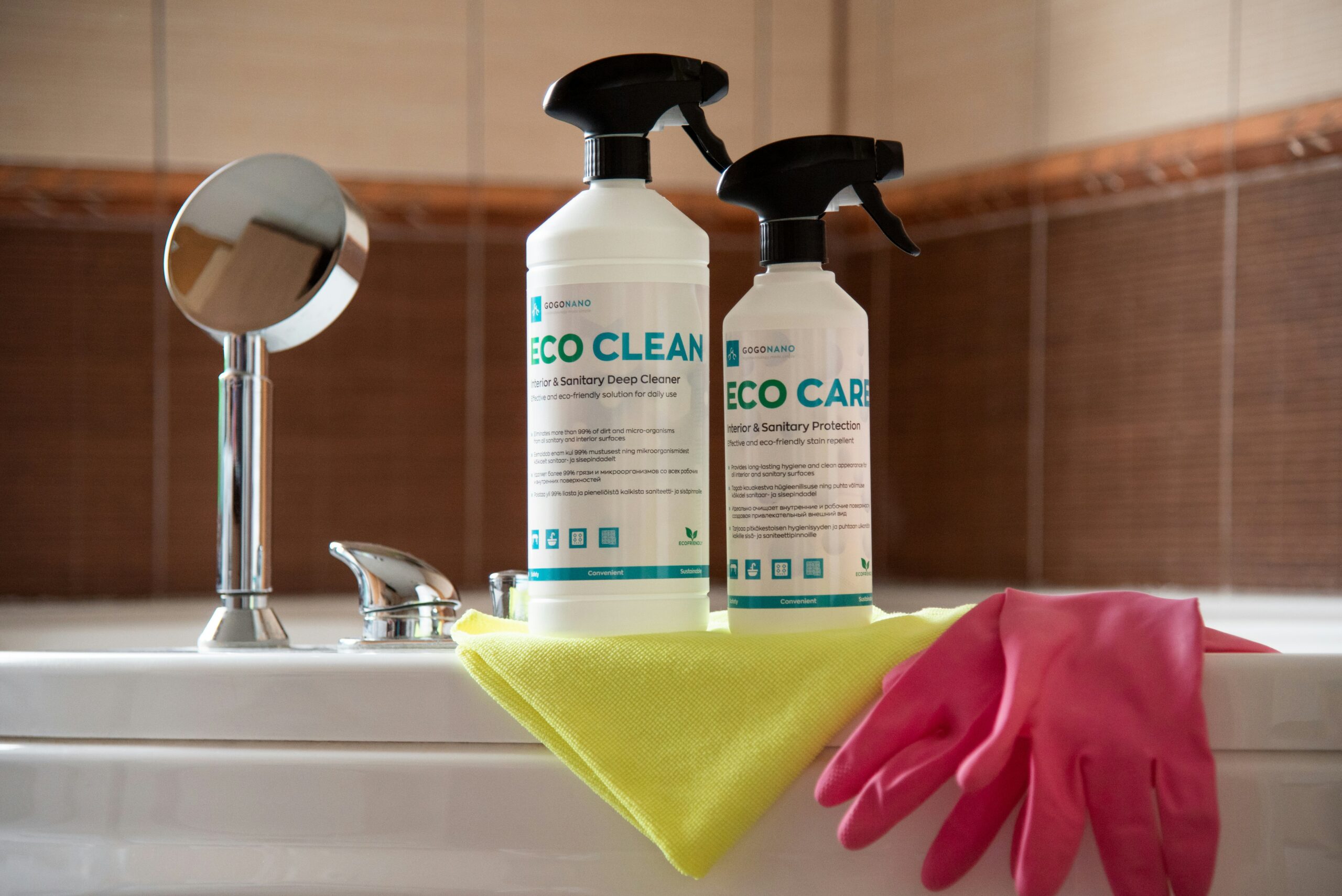 Eco-friendly cleaning supplies, pink gloves, and a yellow cloth on a bathtub with a mirror.