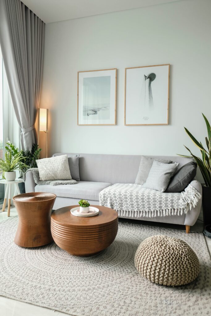 A tidy living area with a white rug, brown tables, and a white sofa.