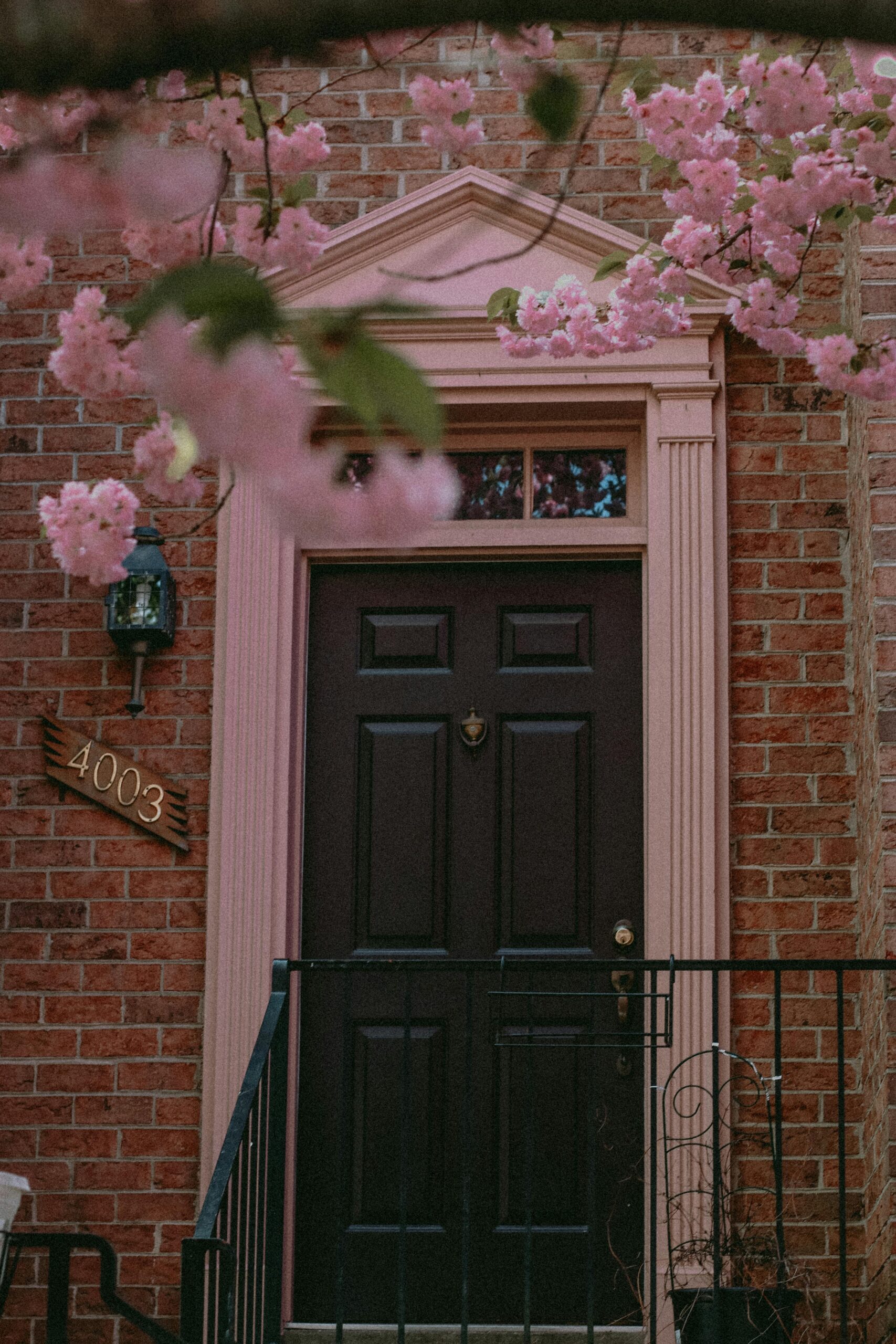 House entrance featuring a large brown door and pink floral decoration above.